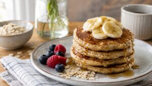 Stack of homemade banana oat pancakes topped with banana slices